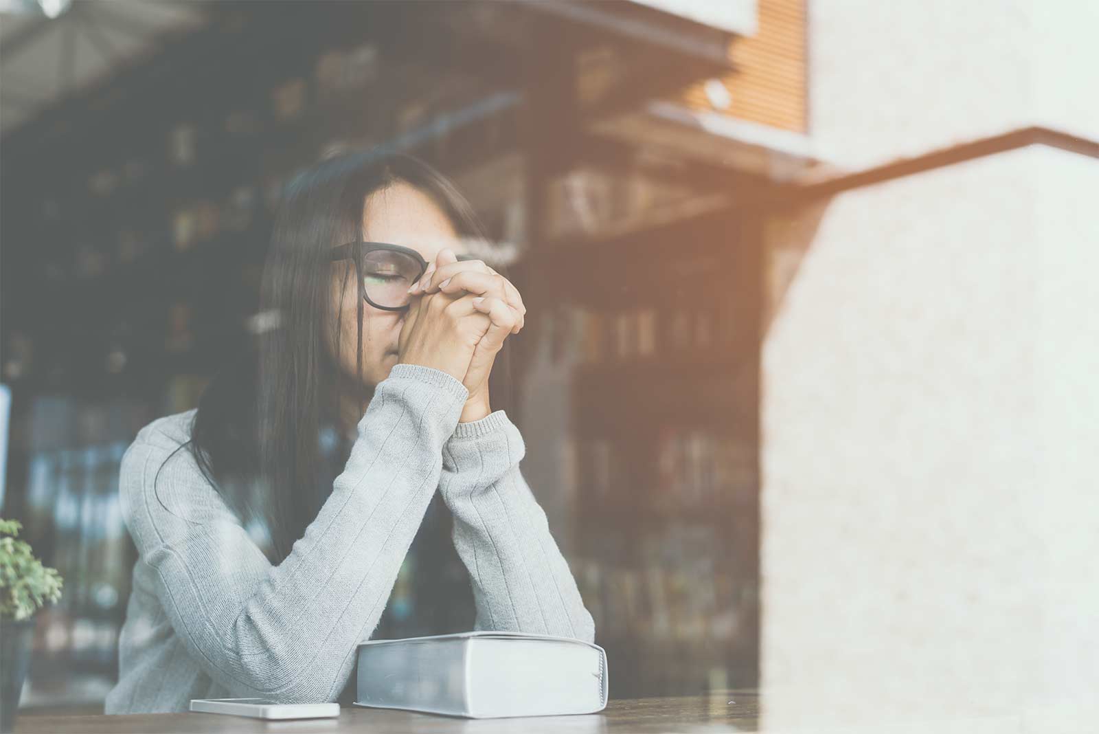 A lady sitting with a troubled face, praying about her worries.