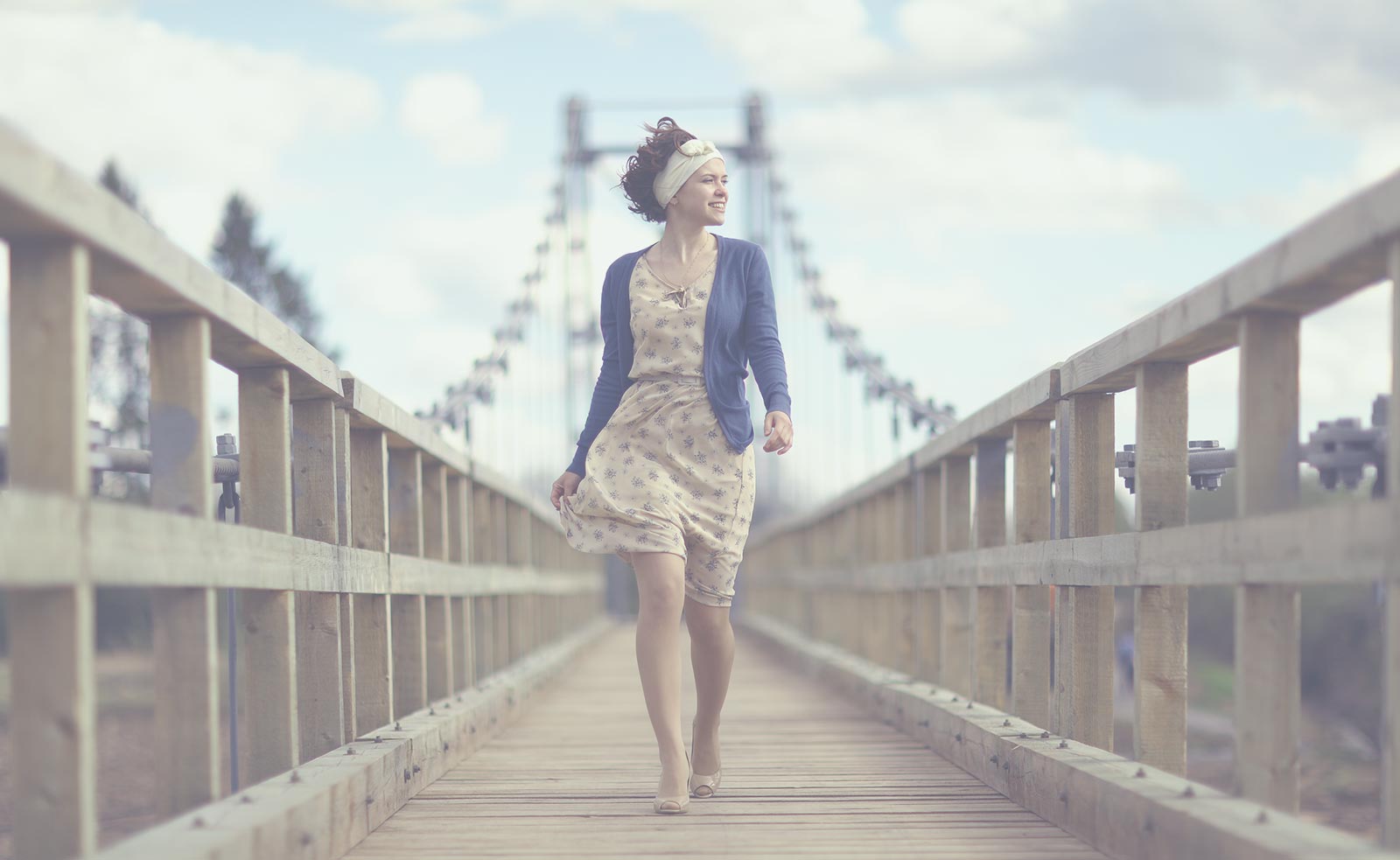 A young adult woman is walking confidently on a bridge.