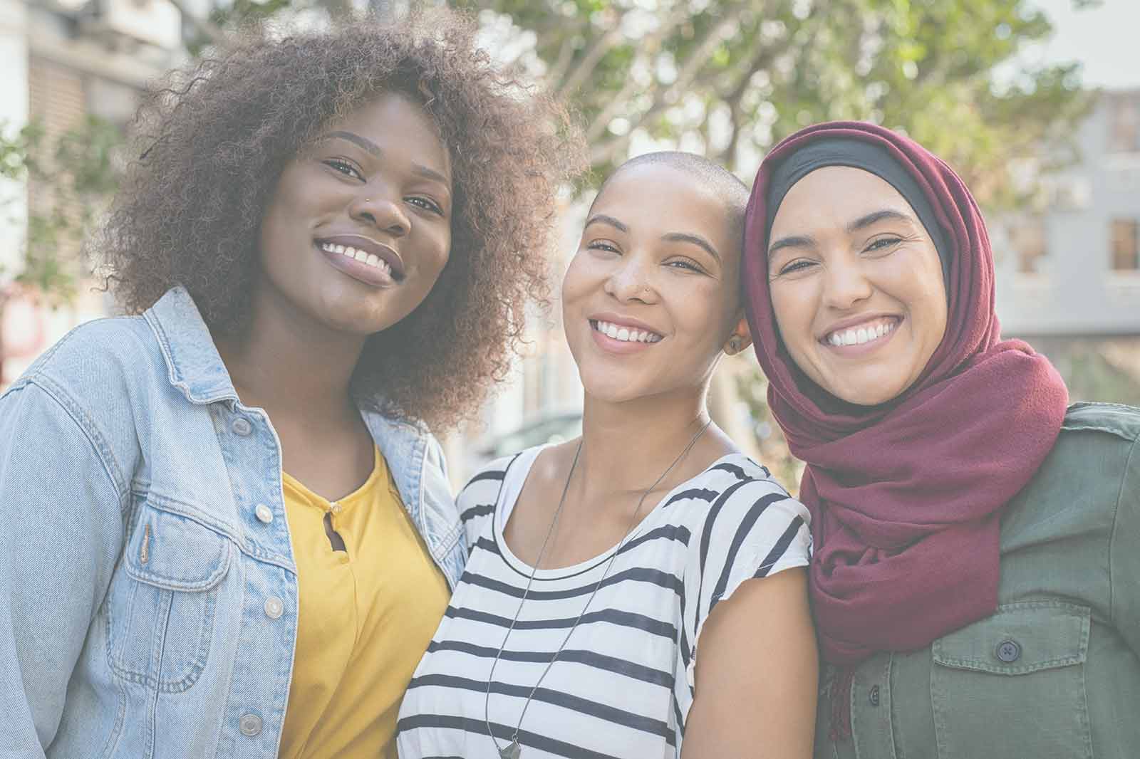 A culturally diverse group of women standing together happily.